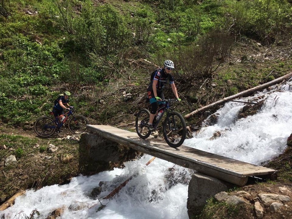 Zwei erwachsene Mountainbiker überqueren eine Holzbrücke